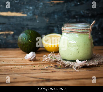 Hausgemachte Creme avocado Dressing in einem Glas auf Holz- Hintergrund Stockfoto