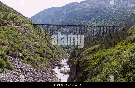 Historische Stahlbrücke über den White Pass Schlucht 18 Meilen nördlich von skagway Alaska von bewaldeten, felsigen Bergen umgeben Stockfoto