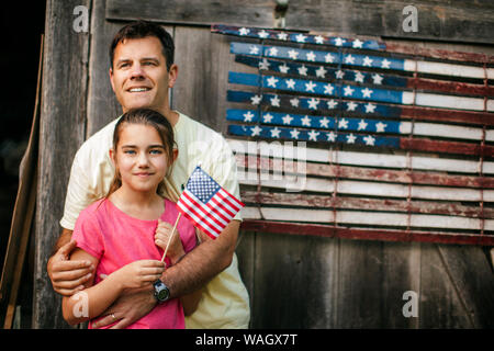 Gerne Vater und Tochter stand vor einer amerikanischen Flagge. Stockfoto