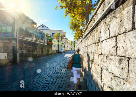 Eine junge Frau geht alleine eine Kopfsteinpflasterstraße Back Street in der Innenstadt von Sorrent, Italien Stockfoto