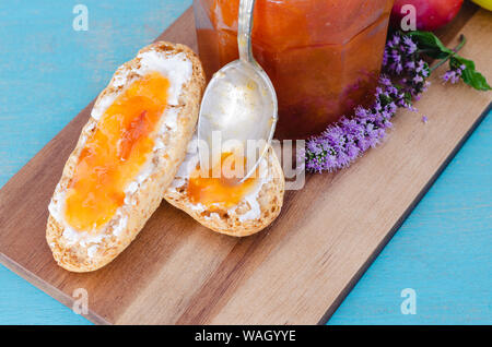 Hausgemachtes Pflaumenmus in Glas Glas auf Holztisch und blauem Hintergrund. Stockfoto