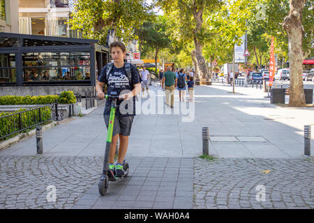 ISTANBUL, Türkei - 5. AUGUST 2019: Völker sind Wandern und Junge reiten auf elektrische Kick scooter. E-Kick-Roller von 'MARTI Tech', die Türkische Stockfoto