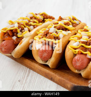 Hausgemachte Coney Island chili Hund auf einem rustikalen Holzbrett auf weißem Hintergrund Holz, Seitenansicht. Close-up. Stockfoto