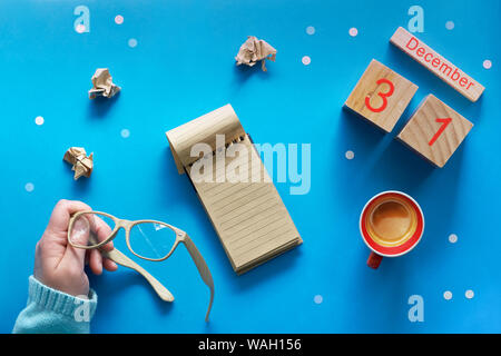 Weihnachten Hände Liste und der Frau mit Stift, Notizbuch, Kalender und Kaffee auf Blau pastell Tabelle Ansicht von oben. Flach Stil, blaues Papier Hintergrund mit Stockfoto