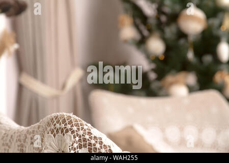 Close up of the back of a cozy cross with a handmade cape on a blurred background of a decorated Christmas tree, selective focus Stockfoto