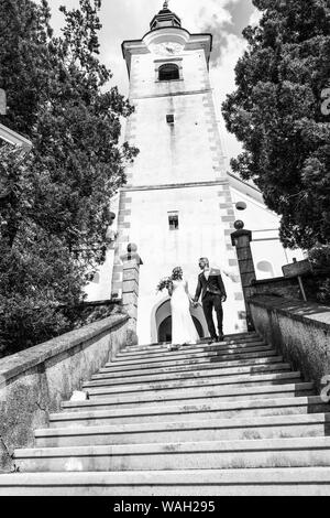 Der Kuss. Braut und Bräutigam Küsse zärtlich auf einer Treppe vor einem kleinen lokalen Kirche. Stockfoto
