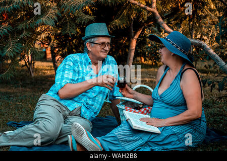Gerne ältere Frau und Mann Wein trinken und genießen romantisches Date in Park Stockfoto