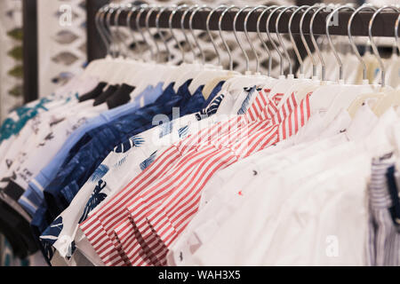 Die Kleiderbügel ist mit farbenfrohen Stoffen shirts gefüllt. saubere Hemden auf Rack in Wäsche aufhängen, Nahaufnahme Stockfoto