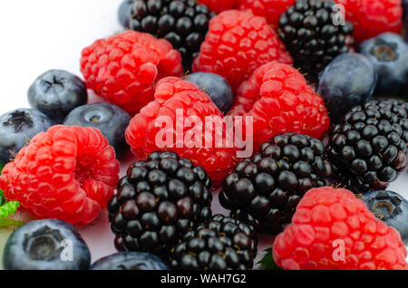 Nahaufnahme Foto von organischen Blaubeeren, Brombeeren, Himbeeren und grüne Blätter gemischt zusammen. Stockfoto