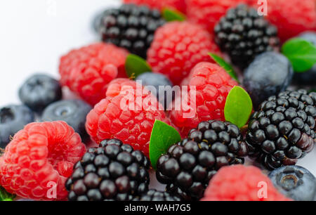 Nahaufnahme Foto von organischen Blaubeeren, Brombeeren, Himbeeren und grüne Blätter gemischt zusammen. Stockfoto