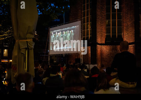 Nijmegen, Gelderland, Niederlande. 20 Aug, 2019. Eine Szene einer der Tarantino Filme auf einer großen Leinwand gesehen. Da der letzte Film von Quentin Tarantino in diesem Monat veröffentlicht wurde, LUX, eine unabhängige und liberale Plattform in Nijmegen für neue Entwicklungen in der Kunst und Kultur angeboten, ein Open-Air-Kino Vorführungen von seinen Bekannten filmen, wie vier Zimmer und Pulp Fiction. Hunderte von Menschen kann man kostenlos die Filme, wie vier Zimmer und Pulp Fiction in einer sehr Tarantino Stil genießen. Credit: Ana Fernandez/SOPA Images/ZUMA Draht/Alamy leben Nachrichten Stockfoto