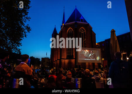 Nijmegen, Gelderland, Niederlande. 20 Aug, 2019. Ein großer Bildschirm wird außerhalb der Kirche, da der letzte Film von Quentin Tarantino in diesem Monat veröffentlicht wurde, LUX, eine unabhängige und liberale Plattform in Nijmegen für neue Entwicklungen in der Kunst und Kultur angeboten, ein Open-Air-Kino Vorführungen von seinen Bekannten filmen, wie vier Zimmer und Pulp Fiction. Hunderte von Menschen kann man kostenlos die Filme, wie vier Zimmer und Pulp Fiction in einer sehr Tarantino Stil genießen. Credit: Ana Fernandez/SOPA Images/ZUMA Draht/Alamy leben Nachrichten Stockfoto