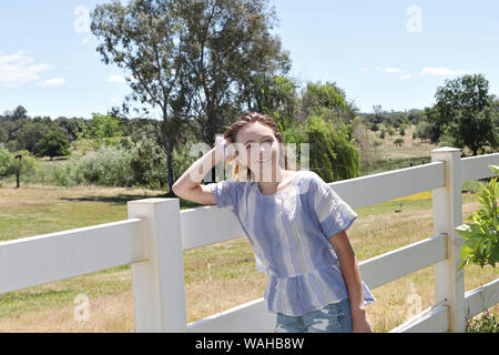 Eine junge jugendmädchen Uhren ihre Stute grasen in einem Feld. Stockfoto