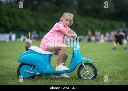 7-Jähriges Mädchen sitzen auf Größe Motorroller ihres Kindes, Großbritannien Stockfoto