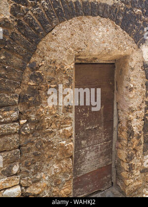 Stony arch und Braun alte Tür des alten Haus in der kleinen mittelalterlichen Stadt Sermoneta in Italien, in Latium. Abstrakte texturierte Oberfläche Muster für Design. Stockfoto