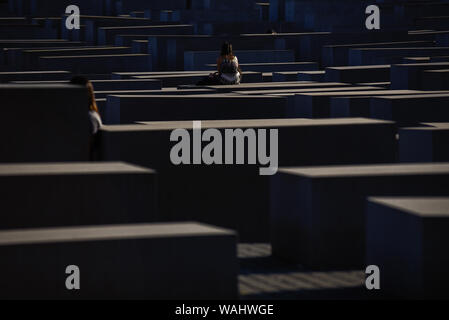 Die Besucher gehen durch Hunderte von betonplatten oder Der telae "Teil des Denkmals für die ermordeten Juden Europas "Holocaust Mahnmal" südlich des Brandenburger Tors. Holocaust Mahnmal wurde von amerikanischen Architekten Peter Eisenman entworfen, auf einer Fläche von 19.000 Quadratmetern von 2711 Betonplatten abgedeckt oder telae'. Stockfoto