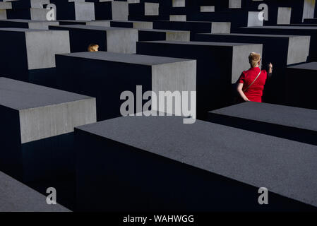 Die Besucher gehen durch Hunderte von betonplatten oder Der telae "Teil des Denkmals für die ermordeten Juden Europas "Holocaust Mahnmal" südlich des Brandenburger Tors. Holocaust Mahnmal wurde von amerikanischen Architekten Peter Eisenman entworfen, auf einer Fläche von 19.000 Quadratmetern von 2711 Betonplatten abgedeckt oder telae'. Stockfoto