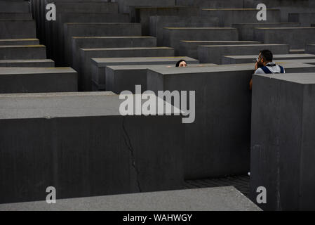 Die Besucher gehen durch Hunderte von betonplatten oder Der telae "Teil des Denkmals für die ermordeten Juden Europas "Holocaust Mahnmal" südlich des Brandenburger Tors. Holocaust Mahnmal wurde von amerikanischen Architekten Peter Eisenman entworfen, auf einer Fläche von 19.000 Quadratmetern von 2711 Betonplatten abgedeckt oder telae'. Stockfoto