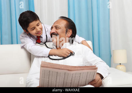 Junge, der seinen Großvater mit Stethoskop untersucht Stockfoto