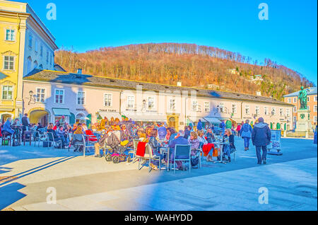 SALZBURG, Österreich - Februar 27, 2019: Das beliebte Café im Freien in Mozartplatz Platz mit umliegenden historischen Handel Bauten und der Mozart Memo Stockfoto