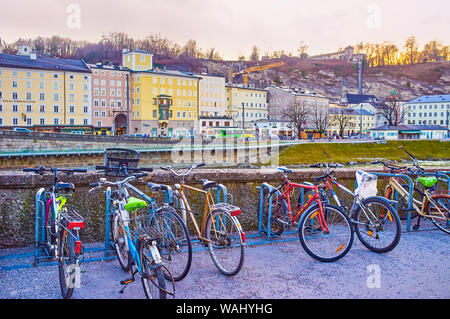 SALZBURG, Österreich - Februar 27, 2019: Das kleine Fahrrad parken am Ufer mit Blick auf die Altstadt am anderen Ufer der Salzach Rive Stockfoto