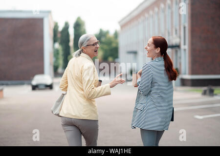 Zwei Business Damen in stilvoller Kleidung lachend im Freien Stockfoto