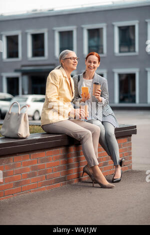 Zwei moderne Frauen auf der Bank sitzen im Freien Stockfoto