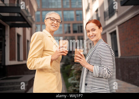 Zufriedene Kollegen lächelnd mit Papier Tassen Kaffee Stockfoto