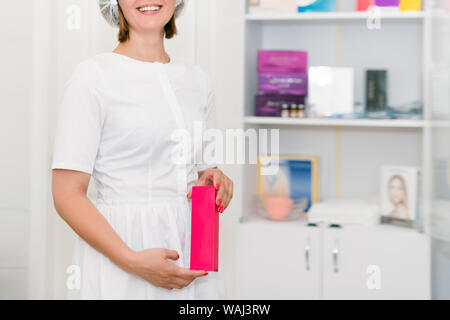 Weibliche Kosmetikerin Holding kosmetische Produkt in der Schönheitsklinik. Kein Gesicht. Arzt Vorbereitung der Patienten für ein kosmetisches Verfahren Stockfoto