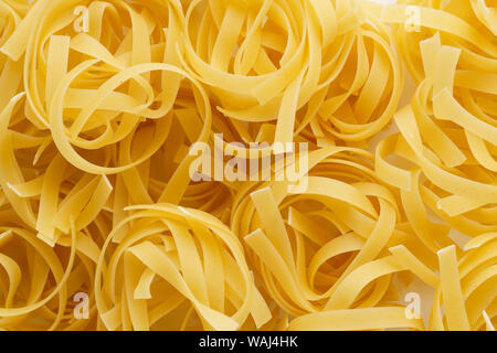 Pasta Hintergrund aus Trocken gegarte tagliatelle Nester. Flach. Stockfoto