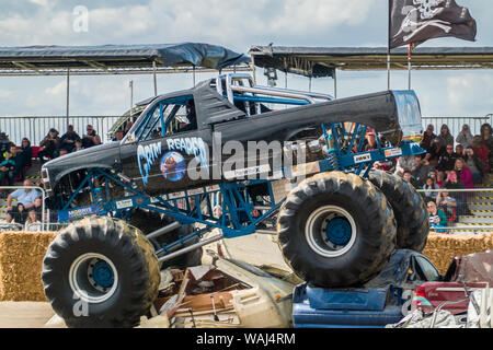 Der Sensenmann Monster Truck fahren über und Zerkleinern von einem Stapel von Schrott Autos während einer Demonstration an einem Monster Truck Show Stockfoto