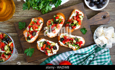 Köstliche Bruschetta mit Ziegenkäse und frischem Gemüse. Knusprigen baguette Scheiben mit Feta, Tomaten, Gurken, Paprika, Oliven, Kräuter. Gesunde br Stockfoto