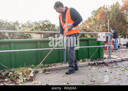 Mann, das Fegen des Fußbodens des Recycling Center nach der Bereitstellung von Abfällen grün Stockfoto