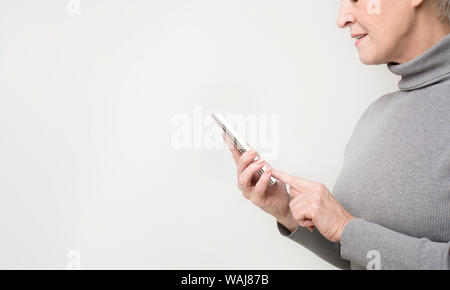 Active Senior Frau surfen auf modernen Smartphone Stockfoto