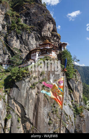 Bhutan, Paro. Gebetsfahnen flattern am Rande der Klippen gegenüber Taktsang Kloster, oder der Tiger Nest. Stockfoto