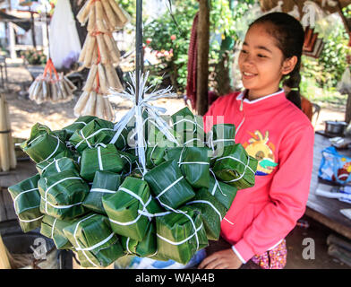 Kratie, Kambodscha. Pakete von klebrigen Reis mit Banane und Kokosnuss, die in Bananenblätter eingewickelt und gedämpft. Für den Verkauf an einer Straße. (Redaktionelle nur verwenden) Stockfoto