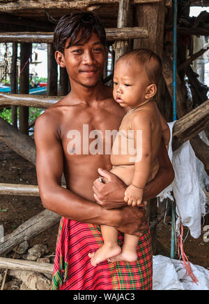 Kompong pluk half (Phluk), Kambodscha. Junger Mann seinen kleinen Sohn Holding. Dies ist ein Cluster aus drei Dörfern von Pfahlbauten in der Aue des Tonle Sap Fluss gemacht. (Redaktionelle nur verwenden) Stockfoto