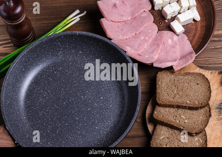 Leeren pan für Text und Zutaten für ein gesundes Frühstück oder Mittagessen. Schinken, Schafskäse und Stücke Brot auf einem braunen Holztisch. Stockfoto