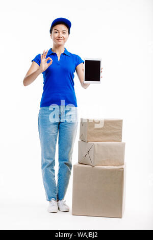 Frau in Lieferung arbeitet, hat drei Pakete, die von Ihrer Seite als Sie hält einen Tablet vor ihr. Stockfoto