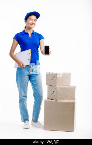 Frau in Lieferung arbeitet, hat drei Parzellen durch Ihre Seite als hält sie ein Telefon vor ihr. Stockfoto