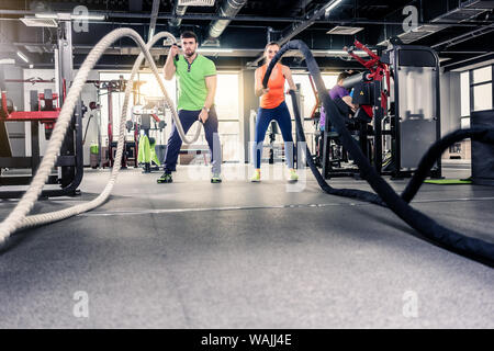 Frau und Mann mit Seil im Fitnessstudio Stockfoto