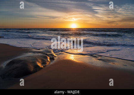 Sonnenuntergang reflektiert das Wasser auf dem Sand des Strandes Stockfoto