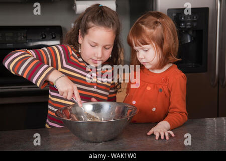 Schwestern rühren Plätzchenteig. (MR, PR) Stockfoto