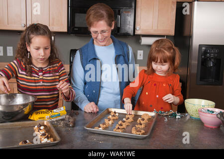 Großmutter und Ihr 4 und 11 Jahre alten Enkelinnen Cookies. (MR, PR) Stockfoto