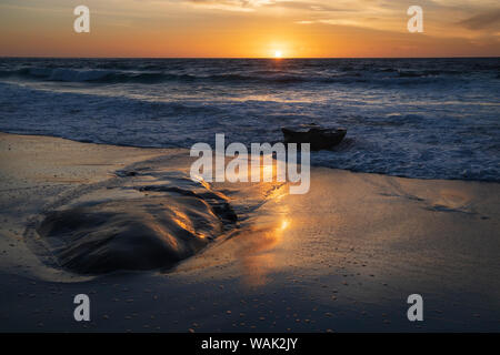 Sonnenuntergang reflektiert das Wasser auf dem Sand des Strandes Stockfoto