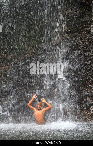 Kosrae, Mikronesien (FSM). Junge Junge spielt in Cascading Spray von Sipyen Wasserfall, (MR) Stockfoto