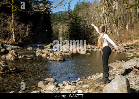 Olallie State Park, in der Nähe von North Bend, Washington State, USA. Neun Jahre altes Mädchen werfen einen Stein in die Luft. (MR) Stockfoto