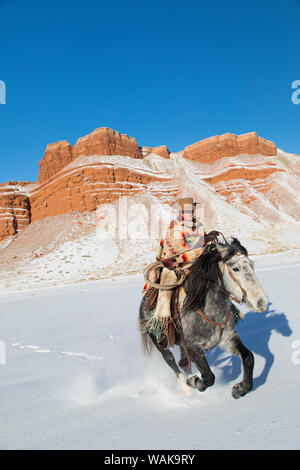 Reiten und Fahren im Winter auf Versteck Ranch, Shell, Wyoming. Cowgirl auf dem Pferd. (MR) Stockfoto