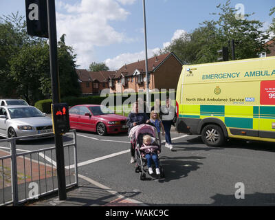 Familie überquert Straße bei einem Unfall Szene auf einen Fußgängerüberweg auf eine zweispurige Straße auf Topp Weg, Bolton, Lancashire, England UK. foto DON TONGE Stockfoto