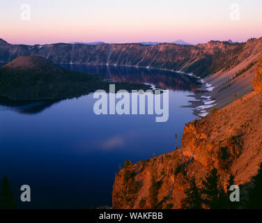 USA, Oregon. Crater Lake National Park, sunrise Licht auf Wizard Island, Aussicht südlich von Merriam Point mit Mount Shasta und Mount McLoughlin in der Ferne sichtbar. Stockfoto